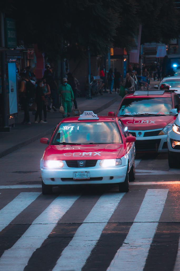 Taxis and traffic on a crowded city street at twilight in Mexico City.
