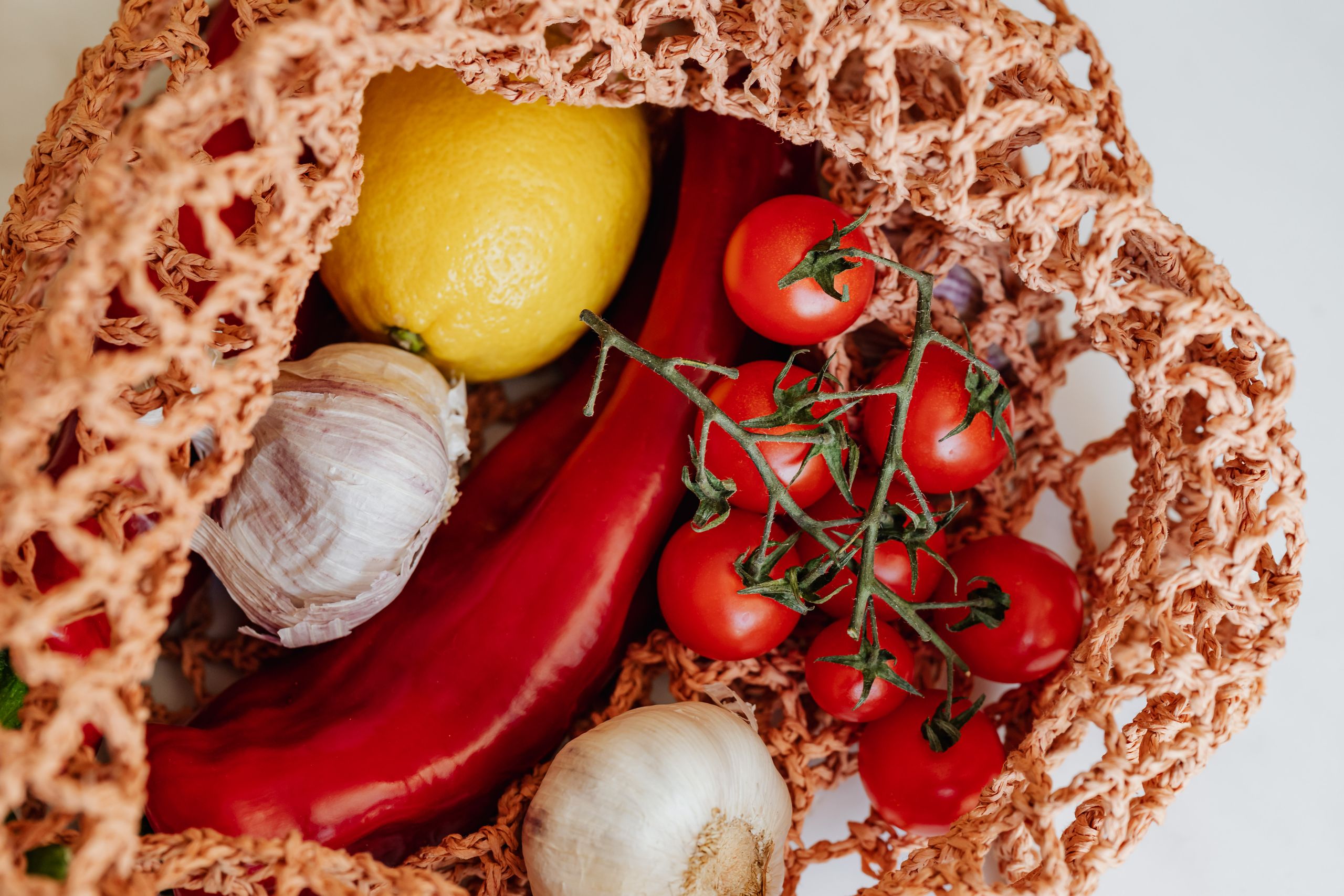 Top view of various fresh ripe vegetables inside of reticular handbag on desktop